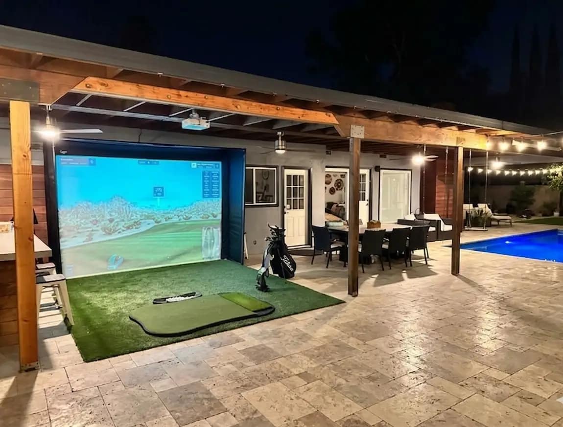 luxury-outdoor-golf-simulator-pool-patio-tampa-fl - Sims & Greens A custom-engineered luxury outdoor golf simulator enclosure installed directly on a residential pool patio in Tampa, Florida, featuring a premium impact screen and artificial turf hitting area situated seamlessly next to the swimming pool.