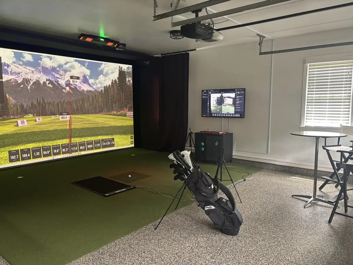 A luxury garage golf simulator conversion in Clearwater, Florida, featuring a high-performance SkyTrak launch monitor, professional-grade hitting mat, and a polished grey epoxy floor.