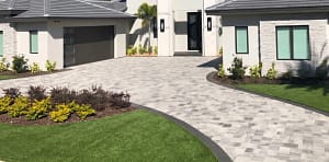 Fake Grass Installation Next to Paver Driveway in St. Petersburg, FL - Sims & Greens Modern home in St. Petersburg, Florida, featuring a clean concrete paver driveway bordered by lush, green artificial grass.