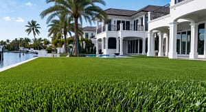 Luxury Waterfront Turf & Composite Decking | Sims & Greens - Sims & Greens Custom salt-resistant artificial turf lawn integrated with a luxury composite deck and a modern gas fire pit in a waterfront Tierra Verde, Florida backyard.