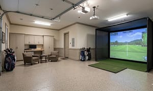 luxury-garage-golf-simulator-office-conversion-seminole-fl - Sims & Greens A multi-functional luxury garage conversion in Seminole, Florida, featuring a professional golf simulator bay, an integrated home office desk, and a lounge area with epoxy flooring.