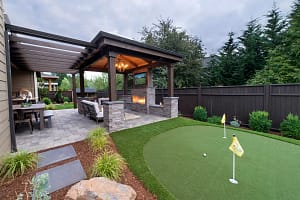 Gazebo-Patio-Outdoor-Kitchen-Putting-Green - Sims & Greens Luxury backyard outdoor living space in Florida featuring a custom artificial putting green, a wood gazebo with a stone fireplace, and a high-end patio with a built-in grill.