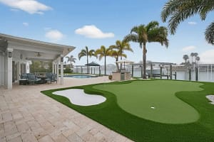backyard-putting-greens-clearwater-fl-bunker - Sims & Greens Custom-engineered backyard putting green in Clearwater, FL, featuring multi-tiered synthetic turf, a professional white sand bunker, and a luxury waterfront pool deck integration.