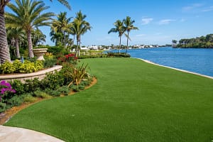 Madeira-Beach-FL-Total-Grass-Replacement-Turf - Sims & Greens Residential artificial turf backyard replacement for a waterfront home in Madeira Beach, Florida, featuring a composite deck and sunset views.