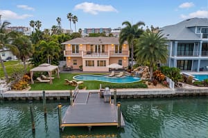 Luxury-Waterfront-Artificial-Turf-Replacement-Florida - Sims & Greens Luxury waterfront home in Florida featuring a full artificial turf lawn replacement surrounding a custom pool and palm trees.