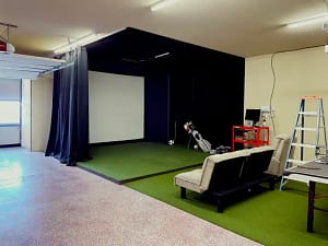 premium-garage-golf-simulator-conversion-clearwater-fl - Sims & Greens A high-end residential garage completely converted into a luxury indoor golf simulator studio in Clearwater, Florida, featuring a custom impact screen enclosure, seamless edge-to-edge artificial turf flooring, and hidden wiring.