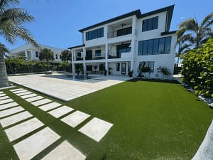 Modern-St-Petersburg-Villa-Synthetic-Lawn-Design - Sims & Greens Modern white villa in St. Petersburg, Florida, featuring luxury artificial turf landscaping, a geometric swimming pool, and tropical palm trees.